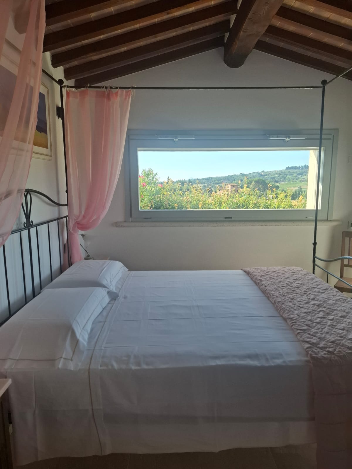 Camera matrimoniale con letto a baldacchino e finestra panoramica sulla campagna